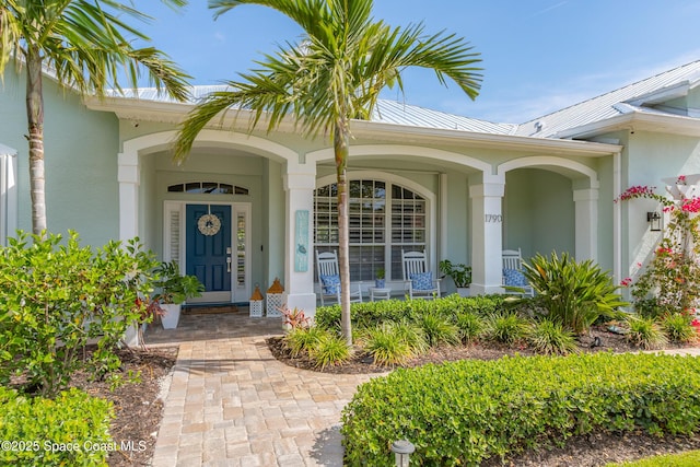 entrance to property featuring covered porch, stucco siding, metal roof, and a standing seam roof