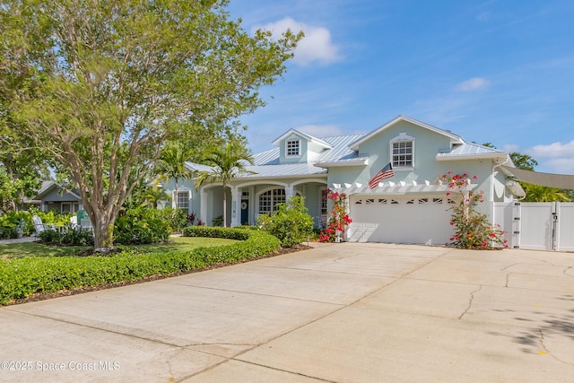 traditional home featuring fence, metal roof, a garage, concrete driveway, and a gate