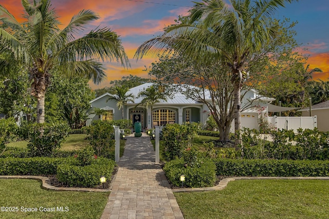 art deco home with a front yard, stucco siding, and fence