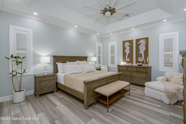 bedroom with recessed lighting, light wood finished floors, a tray ceiling, and visible vents