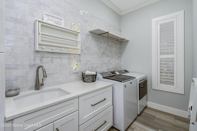 washroom with light wood-style flooring, a sink, separate washer and dryer, cabinet space, and baseboards