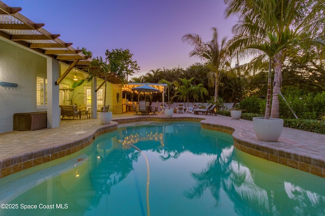 pool at dusk featuring outdoor dining space, a patio, and an outdoor pool