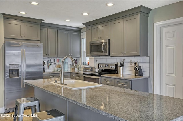 kitchen featuring recessed lighting, a sink, decorative backsplash, dark stone counters, and appliances with stainless steel finishes