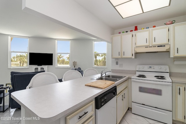 kitchen with a sink, a peninsula, white appliances, under cabinet range hood, and light tile patterned floors