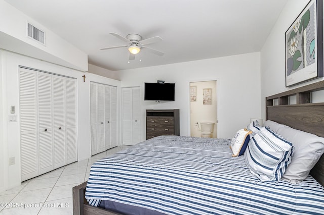tiled bedroom with connected bathroom, two closets, visible vents, and a ceiling fan