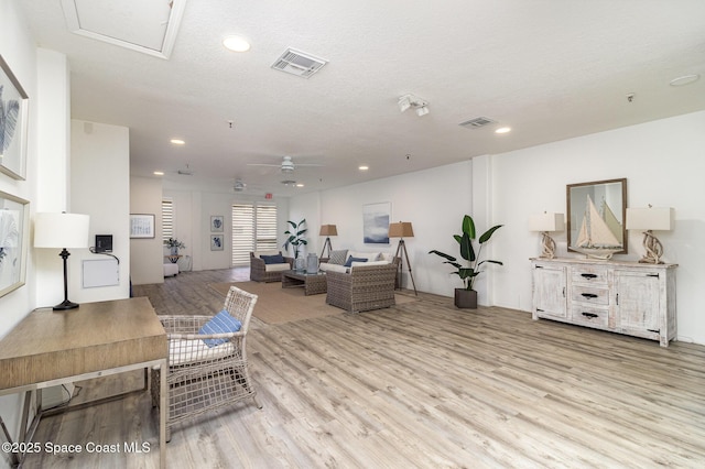 living room with light wood finished floors, a ceiling fan, and visible vents