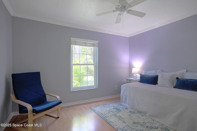 bedroom with light wood-style flooring, ornamental molding, baseboards, and ceiling fan