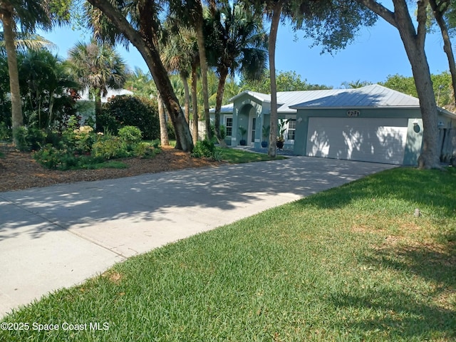 ranch-style home featuring an attached garage, concrete driveway, a front yard, and metal roof