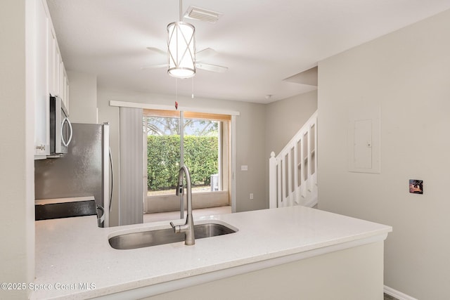 kitchen featuring ceiling fan, a sink, white cabinetry, stainless steel appliances, and a peninsula