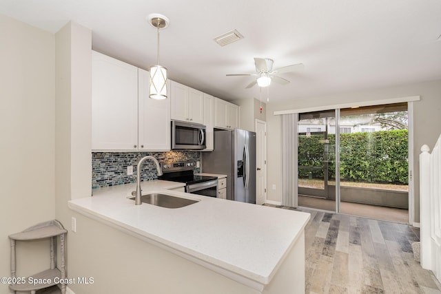 kitchen featuring light wood-type flooring, light countertops, a sink, appliances with stainless steel finishes, and backsplash