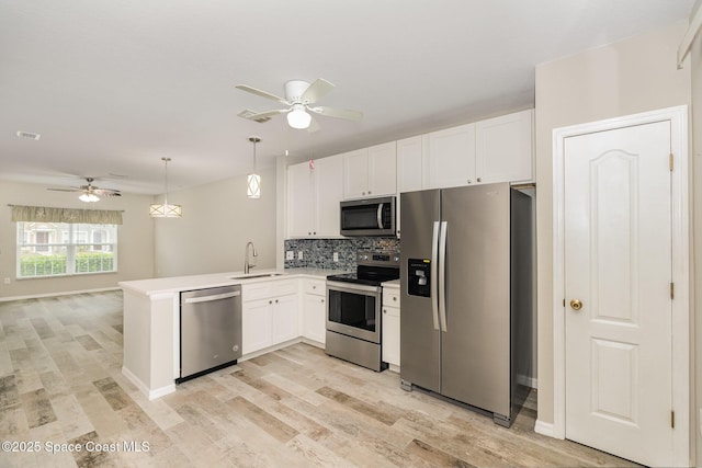 kitchen with a sink, appliances with stainless steel finishes, ceiling fan, and a peninsula