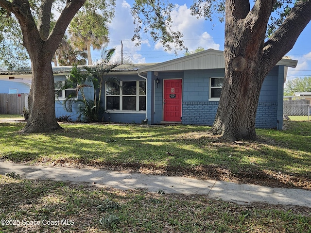 single story home with a front lawn, fence, and concrete block siding