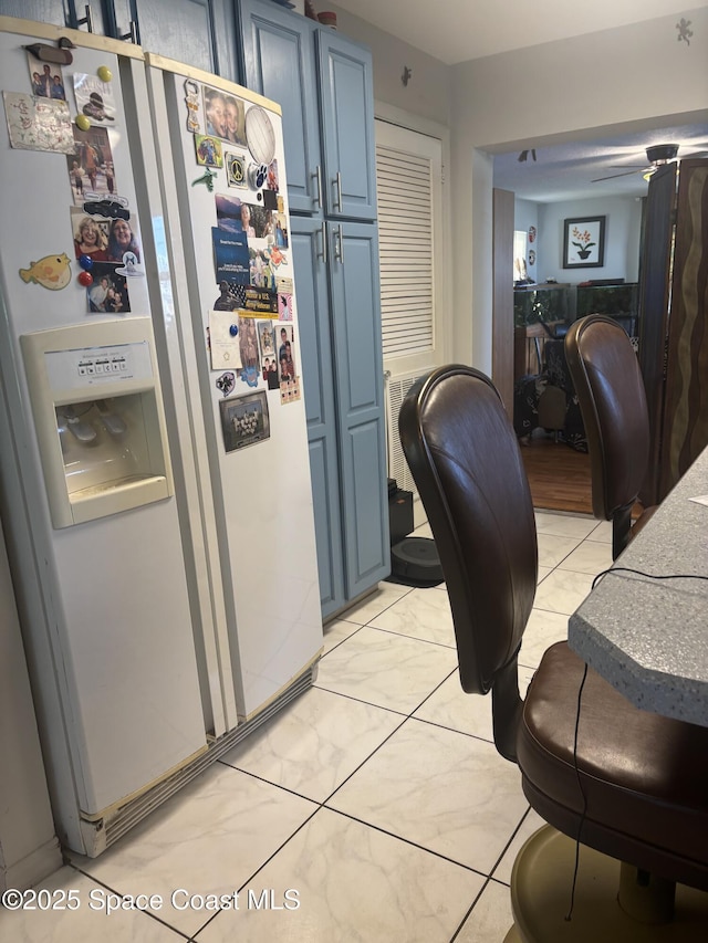 986 Macco Rd, Cocoa, FL 32927 - kitchen featuring white refrigerator with ice dispenser, blue cabinetry, and light tile patterned floors