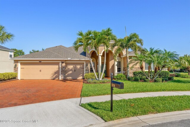 5770 Mascaro Ct, Melbourne, FL 32940 - mediterranean / spanish-style home featuring driveway, an attached garage, stone siding, and a front yard