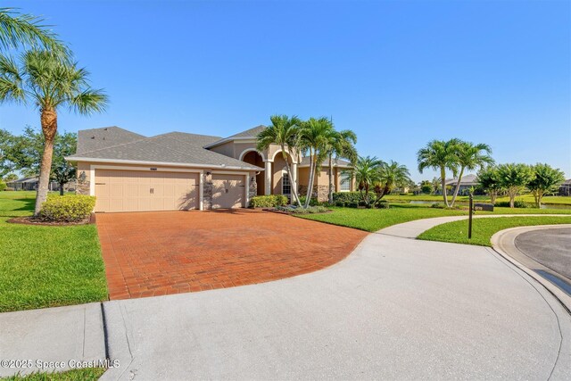 5770 Mascaro Ct, Melbourne, FL 32940 - mediterranean / spanish house featuring decorative driveway, a garage, a front lawn, stucco siding, and stone siding