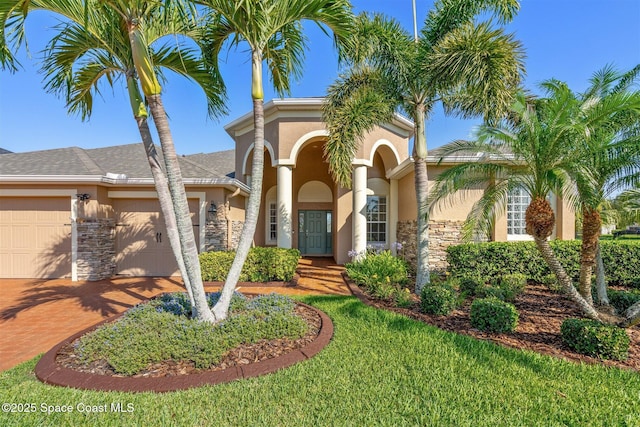5770 Mascaro Ct, Melbourne, FL 32940 - mediterranean / spanish-style home featuring stone siding, stucco siding, decorative driveway, and an attached garage