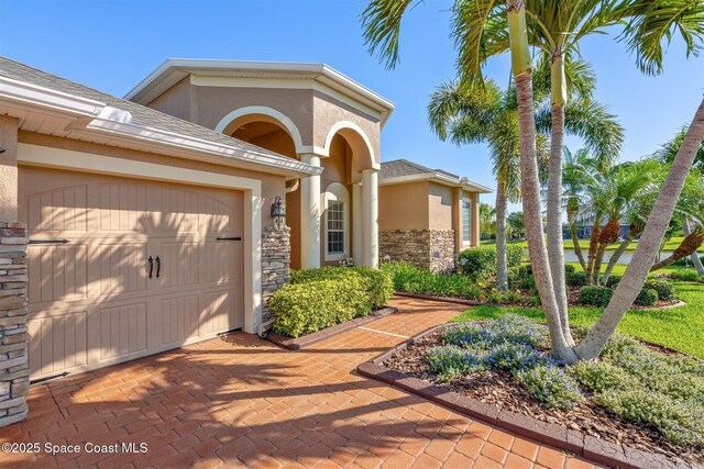 5770 Mascaro Ct, Melbourne, FL 32940 - view of front of house with stone siding, an attached garage, stucco siding, and roof with shingles