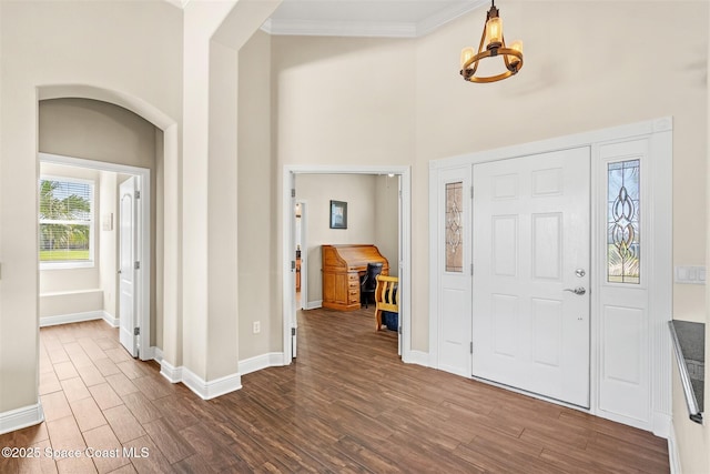 5770 Mascaro Ct, Melbourne, FL 32940 - entrance foyer featuring a chandelier, dark wood-type flooring, baseboards, crown molding, and a high ceiling