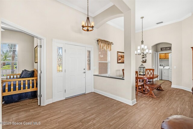 5770 Mascaro Ct, Melbourne, FL 32940 - foyer with a chandelier, separate washer and dryer, arched walkways, wood finished floors, and baseboards