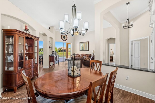 5770 Mascaro Ct, Melbourne, FL 32940 - dining room featuring a chandelier, arched walkways, baseboards, a high ceiling, and crown molding