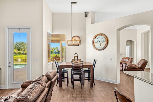 5770 Mascaro Ct, Melbourne, FL 32940 - dining area featuring arched walkways, healthy amount of natural light, wood finished floors, baseboards, and a high ceiling
