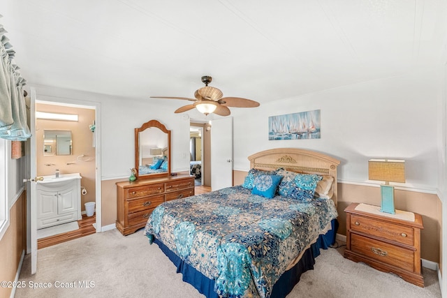 bedroom featuring ensuite bathroom, light carpet, baseboards, and ceiling fan