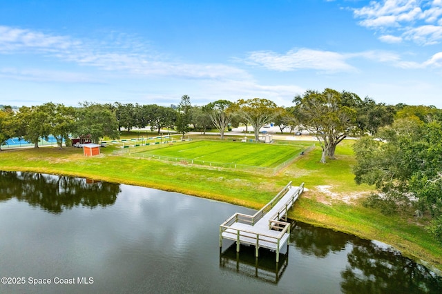 view of dock with a water view and a lawn