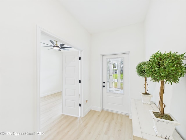 doorway with baseboards, light wood-style flooring, and a ceiling fan