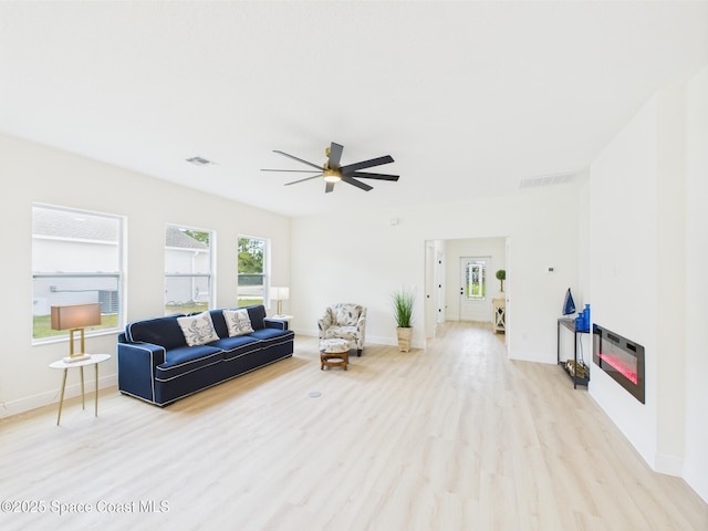 living area with light wood finished floors, baseboards, a ceiling fan, and visible vents