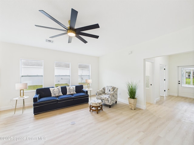 living room with light wood finished floors, baseboards, a ceiling fan, and visible vents