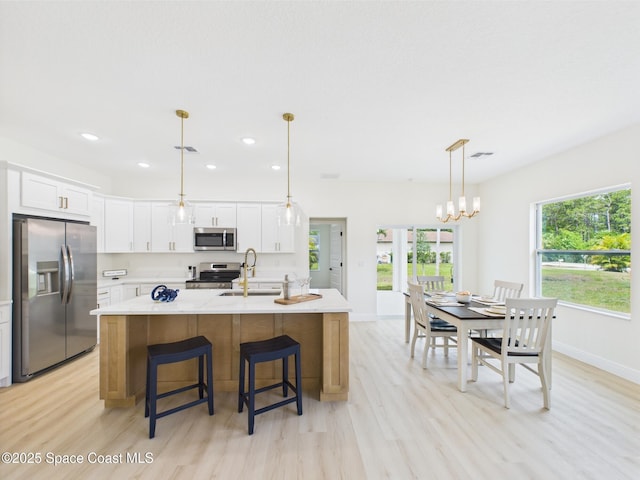 kitchen with a sink, recessed lighting, light wood-style flooring, white cabinets, and appliances with stainless steel finishes