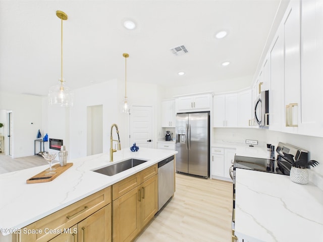 kitchen featuring visible vents, light wood-style flooring, appliances with stainless steel finishes, and a sink