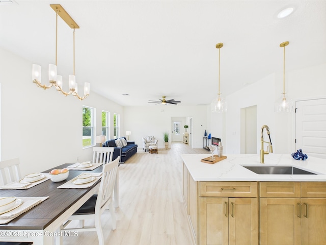 kitchen featuring a ceiling fan, a sink, light brown cabinets, open floor plan, and light wood-style floors