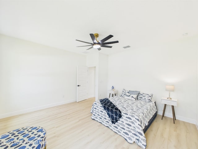 bedroom with baseboards, ceiling fan, visible vents, and wood finished floors