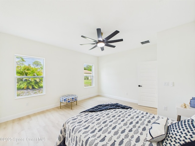 bedroom featuring ceiling fan, light wood-style flooring, baseboards, and visible vents