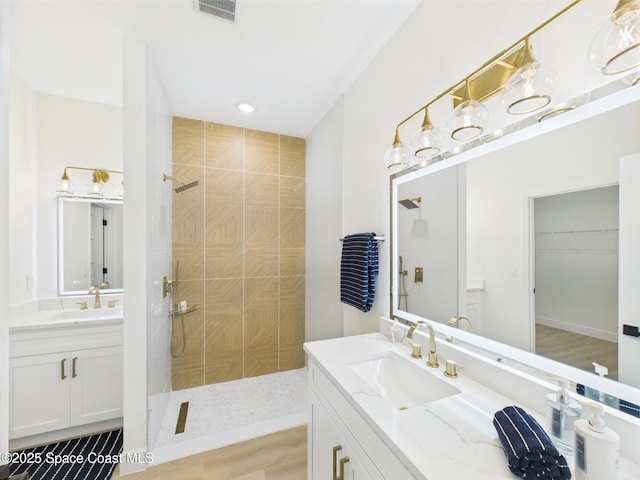 bathroom featuring two vanities, walk in shower, visible vents, and a sink