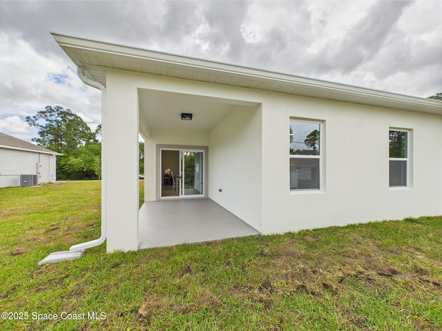 rear view of house featuring cooling unit, a patio, stucco siding, and a yard