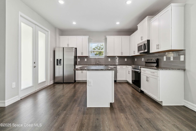 780 Geddes St SW, Palm Bay, FL 32908 - kitchen with appliances with stainless steel finishes, backsplash, a kitchen island, dark wood-style floors, and white cabinets