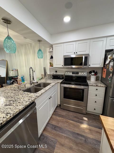 kitchen with a sink, white cabinets, wood counters, and appliances with stainless steel finishes