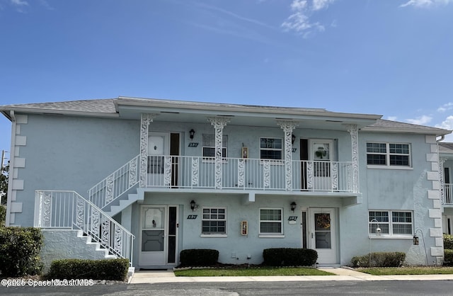 view of front of home with stucco siding, stairway, and a porch