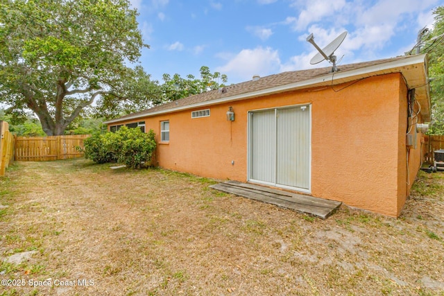 rear view of house with stucco siding and central AC