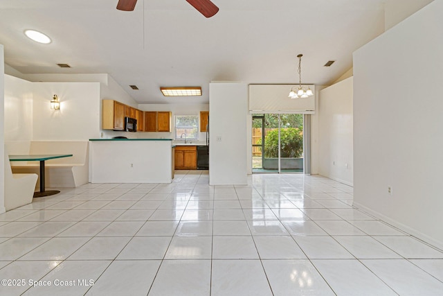 unfurnished living room with light tile patterned floors, a ceiling fan, a sink, and a chandelier