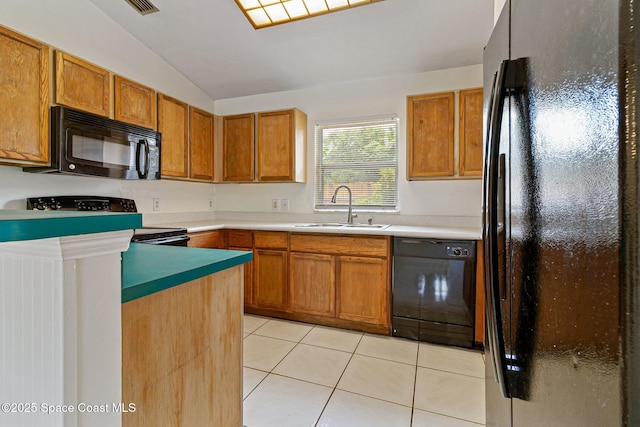 kitchen featuring black appliances, a sink, vaulted ceiling, light tile patterned flooring, and brown cabinets