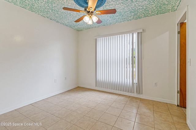 empty room featuring a ceiling fan, light tile patterned floors, and baseboards