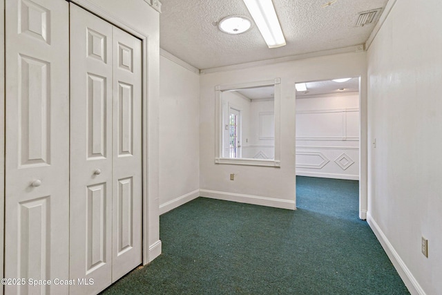 unfurnished room featuring dark carpet, a textured ceiling, and baseboards