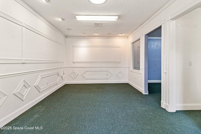 empty room featuring carpet flooring, a textured ceiling, and a decorative wall