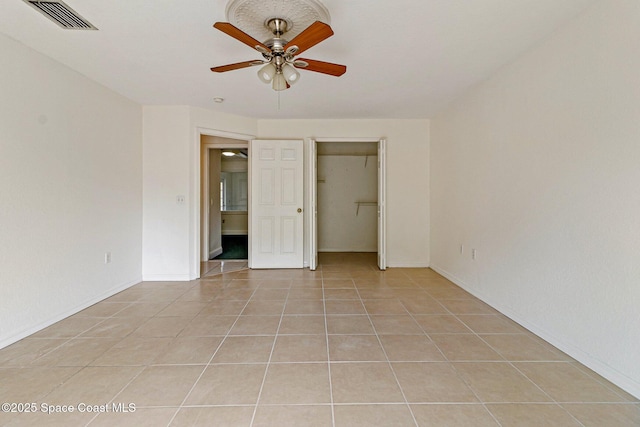 unfurnished bedroom with light tile patterned floors, ceiling fan, a closet, and baseboards