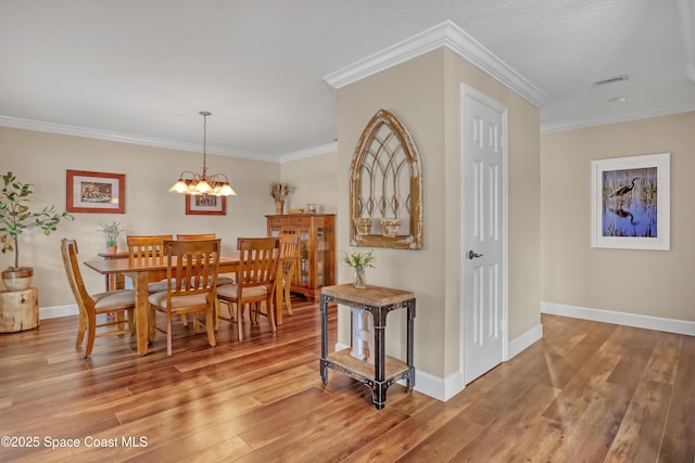 dining space with a chandelier, visible vents, wood finished floors, and baseboards