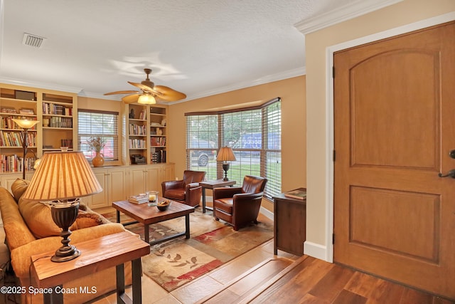 sitting room with ceiling fan, ornamental molding, a wealth of natural light, and wood finished floors