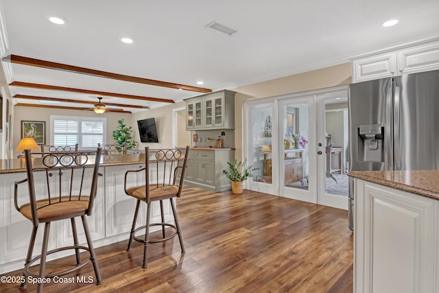 kitchen featuring french doors, stainless steel refrigerator with ice dispenser, a breakfast bar area, visible vents, and dark wood-type flooring
